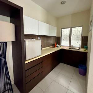 a kitchen with a white refrigerator and a sink at Gold Coast Morib Apartment in Banting