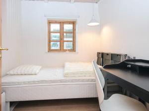 a bed in a room with a desk and a window at House with beautiful garden in Glesborg