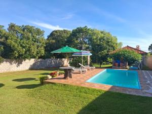 a swimming pool with an umbrella and a table and an umbrella at Chácara Florida Boituva in Boituva