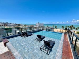 a swimming pool on top of a building with chairs at Cabo Branco - Legacy Suítes in João Pessoa