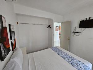 a white room with a bed and a television at Alojamiento en las Huertas in Barrio Nuevo +15 photos