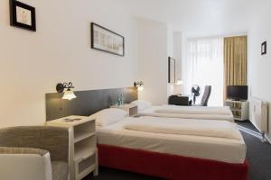 ein Hotelzimmer mit 2 Betten und einem Stuhl in der Unterkunft Aparthotel VEGA in Berlin