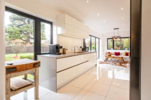 a kitchen with white cabinets and a living room at Beautiful 5 Bedroom Home in Evesham in Evesham