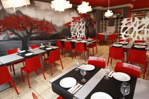 un comedor con mesas y sillas rojas en Hotel Ceao en Lugo