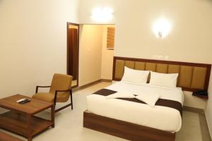 a bedroom with a bed and a chair and a table at Kalathil Kshetra Inn in Guruvāyūr