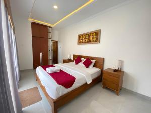 a bedroom with a large bed with red pillows at Villa Sinyo By Mentaripro Bali in Lovina +3 photos