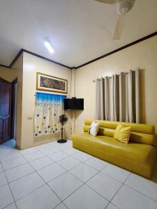 a yellow couch in a living room with curtains at Hibiscus Dive Inn in Pooc