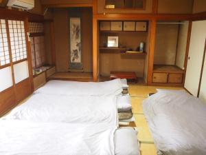 a room with a bed with white sheets on it at Ichie in Tanabe
