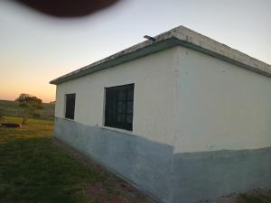 a white building with a window in a field at Don Ramón in Colonia del Sacramento