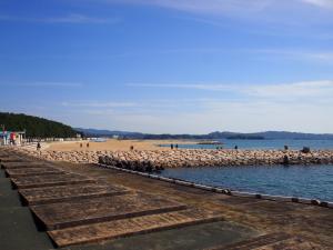 a beach with a pier and people on the beach at Ichie in Tanabe