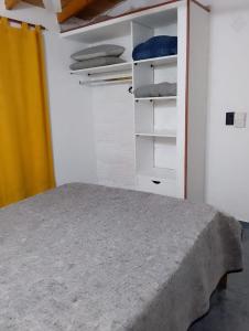 a room with a bed and a closet with shelves at Tomás in Mar de Ajó