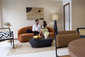 a man and woman sitting on a couch in a living room at Maison Le Patio Jacuzzi in Saint-Denis