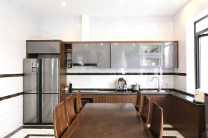 a kitchen with a table and a stainless steel refrigerator at VITA Homestay in Cat Ba