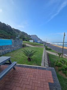 a bench sitting on the side of a sidewalk next to the beach at Umdloti Luxe Horizon in Umdloti