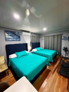 two beds in a room with green sheets at Sunshine Cabanas At Ocean View in Dangriga +30 photos