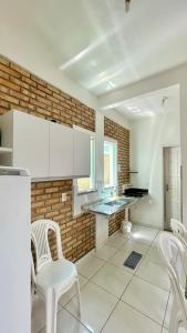 a kitchen with white chairs and a brick wall at Chalés Santo Antônio em Flecheiras in Flecheiras +18 photos