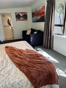 a bedroom with a bed and a couch at Queen Charlotte Bach in Linkwater