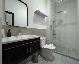 a bathroom with a sink and a toilet and a shower at And Living Hotel in Kejayan