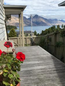 a wooden walkway with red flowers on a house at Lakeview QT in Queenstown