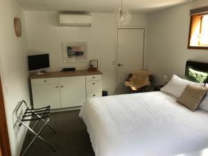 a bedroom with a bed and a desk with a television at Lakeview QT in Queenstown