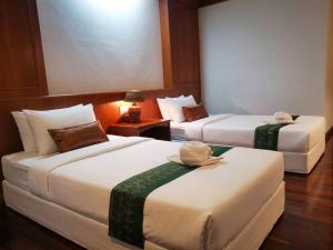 a hotel room with two beds with hats on them at Lanna Oriental Maejo in Chiang Mai