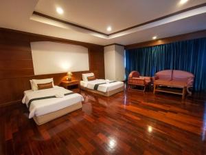 a hotel room with two beds and a chair at Lanna Oriental Maejo in Chiang Mai +62 photos