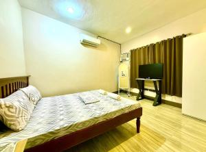 a hotel room with a bed and a television at Boboy's Guest House in Daro