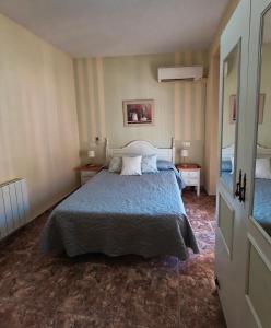 a bedroom with a bed and two tables and a mirror at Hostal Rural Gloria in Graena