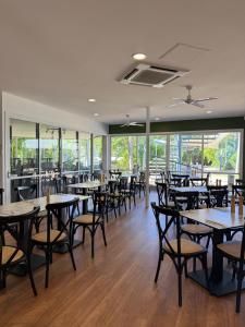 a dining room with tables and chairs and windows at Kellys Beach Resort in Bargara