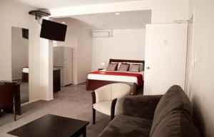 a living room with a bed and a couch and a room at At Eden Park Motel in Auckland