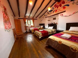 a room with three beds in a room at Willka Lodge in Ollantaytambo