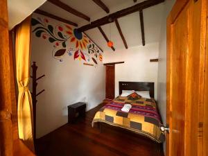 a bedroom with a bed with a painting on the wall at Willka Lodge in Ollantaytambo