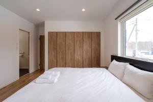 a bedroom with a large white bed with a wooden headboard at Soga House in Niseko