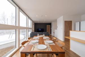 a dining room with a long wooden table and chairs at Soga House in Niseko
