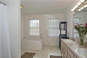 a white bathroom with a tub and two sinks and a bath tub at The Happy Heron in West Cape May +27 photos