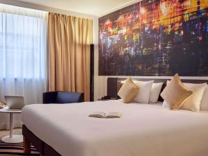a hotel room with a bed with a book on it at Novotel Paris Centre Bercy in Paris