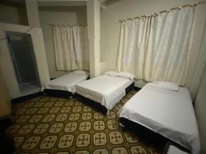 three beds in a small room with curtains at hotel vaticano in Estación El Salto