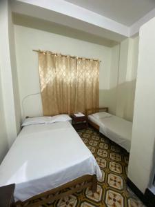 two beds in a small room with a window at hotel vaticano in Estación El Salto
