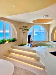 a woman sitting on the stairs in a bathroom with a tub at Meomulda Subyeon in Busan