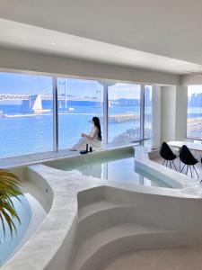 a woman sitting in a room with a view of the water at Meomulda Subyeon in Busan