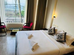 a bedroom with a large bed with two chairs and a window at The Thekkady Haritham Residency in Thekkady