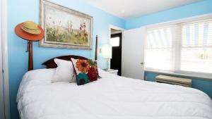 a blue bedroom with a white bed with a flower pillow at The Roost Ii On Leaming in West Cape May