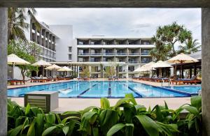 a swimming pool with a hotel in the background at Goldi Sands Hotel in Negombo
