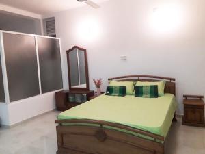 a bedroom with a bed with green sheets and pillows at The white house in Kelaniya