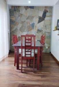 a wooden table with four chairs and a stone wall at The white house in Kelaniya