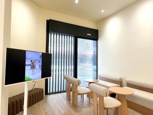 a living room with a tv and a table and chairs at 逢甲25行館Fengjia 25 Hotel in Taichung