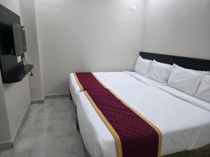 a large white bed in a room with a tv at RK Residency in Tirupati