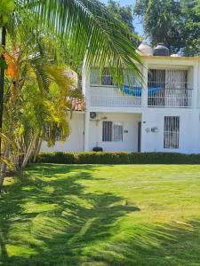 a white house with a palm tree in front of it at Casa Golden in Barrio Nuevo