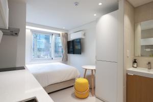 a small bedroom with a bed and a kitchen at 더 신촌스테이 레지던스 in Seoul