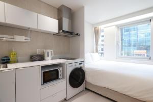 a small bedroom with a bed and a microwave at 더 신촌스테이 레지던스 in Seoul